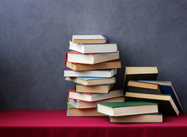 Bir kitap bir kırmızı masa örtüsü ile masada yığını.