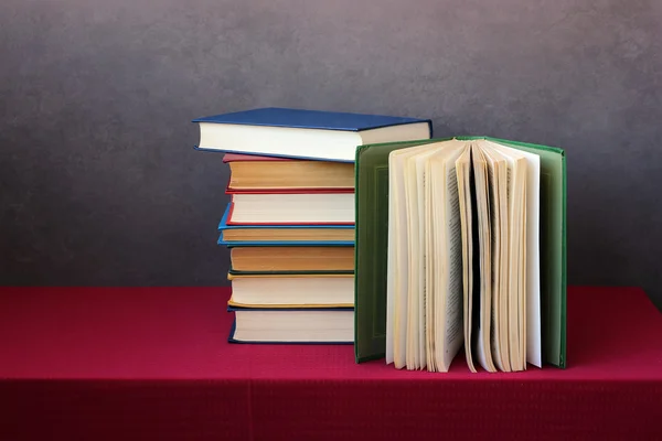 Una pila di libri sul tavolo con una tovaglia rossa . — Foto Stock