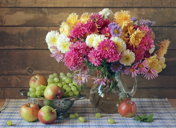 Still life in rustic style with chrysanthemums, grapes and apple — Stock Photo, Image