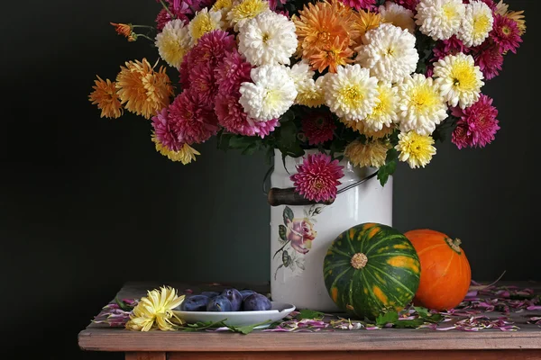Осенний натюрморт с хризантемами в жести, сливах и насосе — стоковое фото