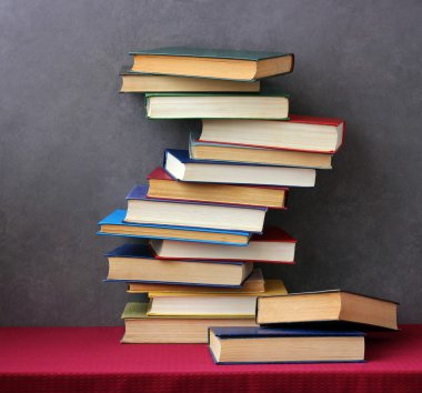 Kırmızı bir masa örtüsü ile masada kitap yığını.