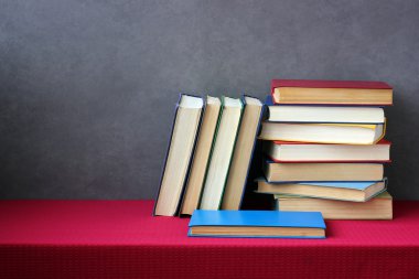 Kırmızı bir masa örtüsü ile masada kitap yığını.
