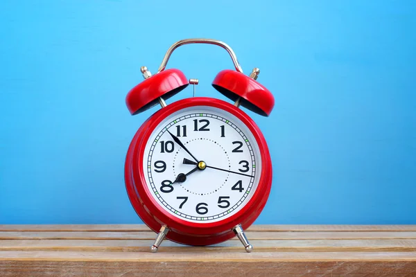 Reloj despertador rojo retro sobre fondo azul . — Foto de Stock