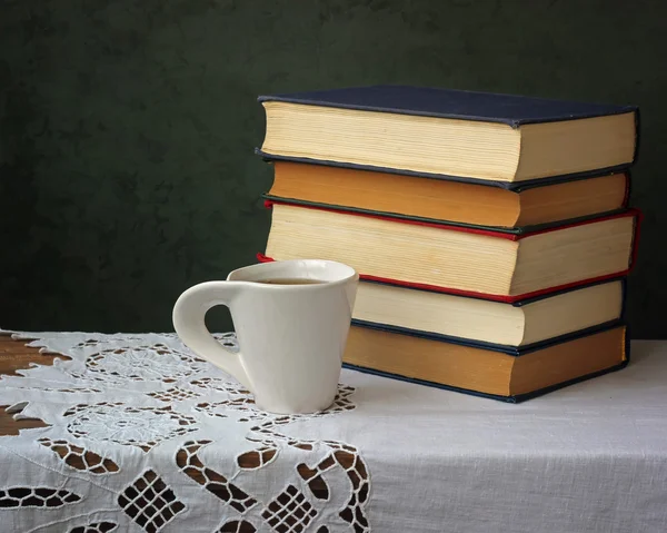 Een stapel boeken en kopje thee op de tafel met een witte tablec — Stockfoto