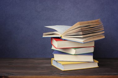 Bir tablo üzerinde kitap yığını. Açık bir kitap.