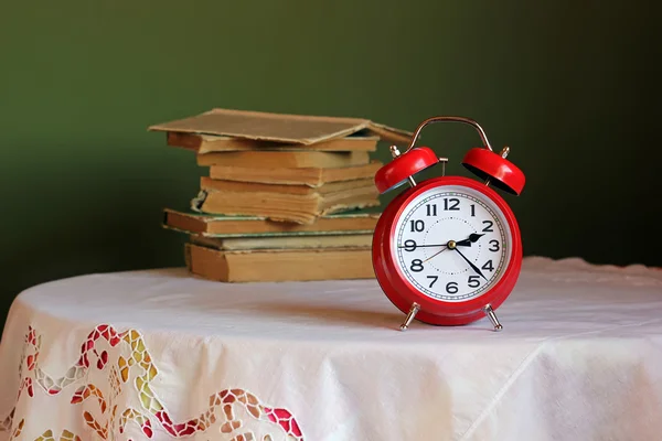 Reloj despertador retro rojo en la mesa con mantel blanco . — Foto de Stock