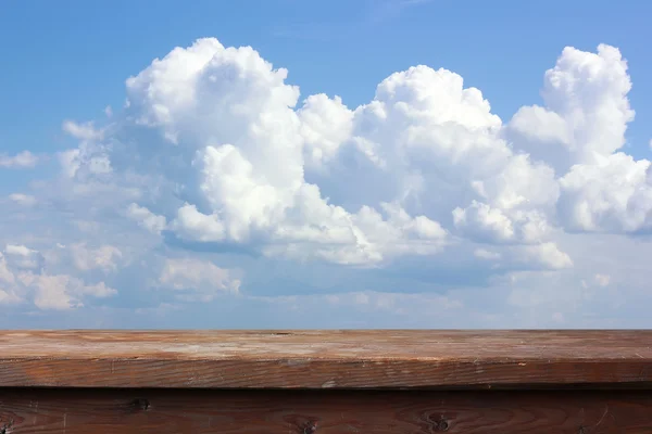 Mesa de madeira vazia em um fundo do céu com nuvens . — Fotografia de Stock