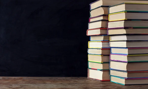 Libros en pilas sobre la mesa en el fondo de una escuela negro —  Fotos de Stock