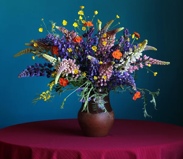 Stilleven boeket met lupine en boterbloemen in een kruik op een blauw — Stockfoto