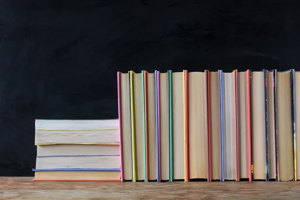 Böcker på hyllan i bakgrunden av en skola svart tavla. — Stockfoto