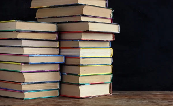 Книги в стопках на столе на фоне школьного черного — стоковое фото