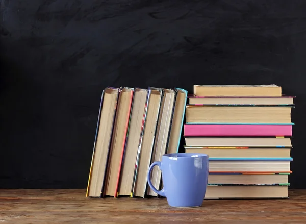 Livros em pilhas no fundo de um quadro-negro da escola . — Fotografia de Stock