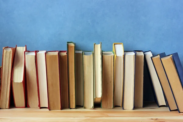 Böcker på en hylla mot en blå vägg. — Stockfoto
