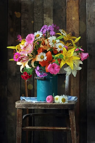 Bouquet of garden flowers in a blue jug on a chair. — Stock Photo, Image