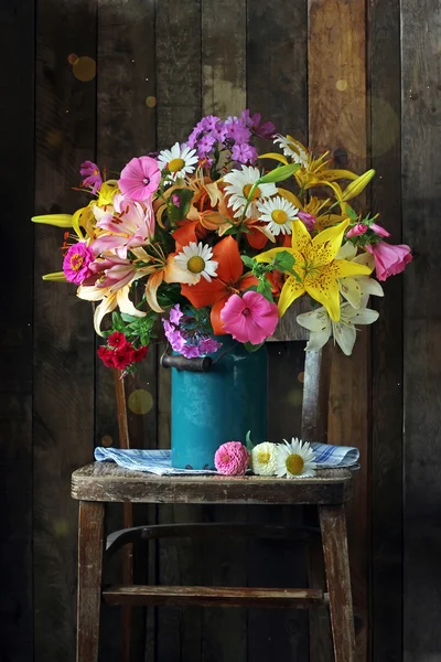 Strauß Gartenblumen in einem blauen Krug auf einem Stuhl. — Stockfoto