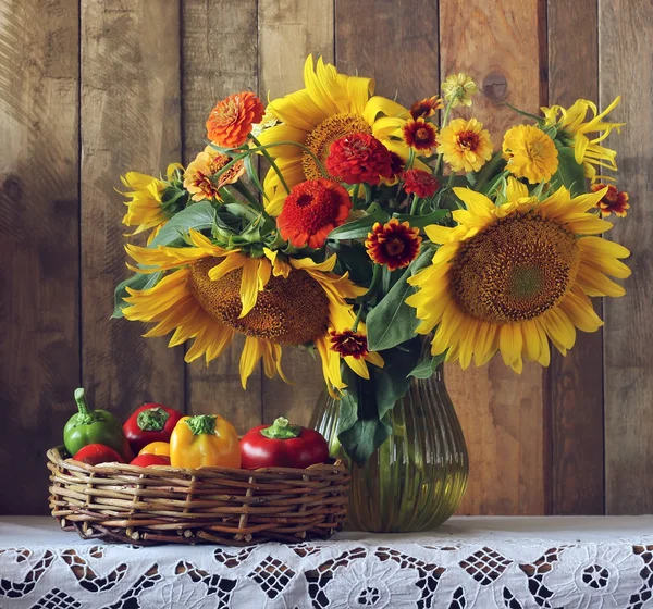 Stillleben mit Sonnenblumen und Paprika im Korb. — Stockfoto