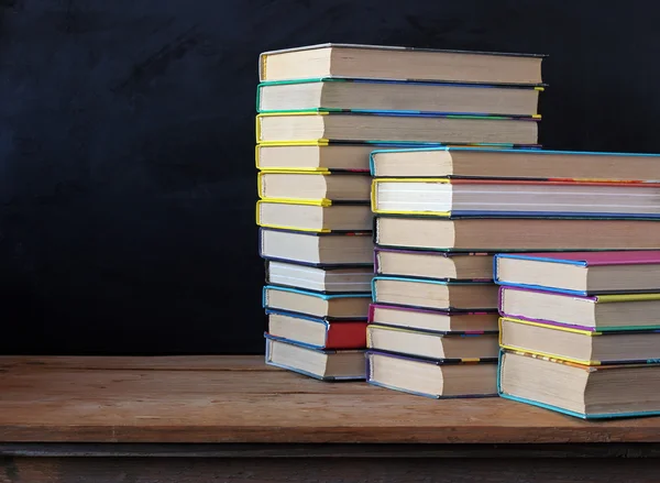 Books in stacks in the background of a school blackboard. — Stock Photo, Image