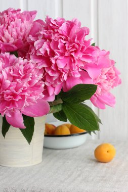 Emaye kabında pembe şakayık ve kayısı buketi, yumuşak yaz imajı..