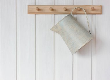 Teneke sürahi beyaz duvardaki askıda asılı. Kırsal iç mekan, arka plan. Boşluğu kopyala.