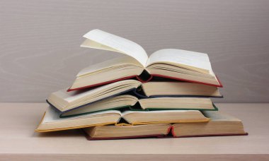 Masada bir yığın açık kitap var. Renkli kapaklarda klasik edebiyatın kağıt ciltleri.