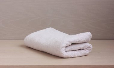 Masanın üzerinde katlanmış beyaz bir havlu. Duş için yumuşak pamuklu havlu..