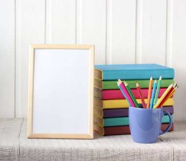 Okul kompozisyonu boş bir çerçeve, bir yığın ders kitabı ve renkli kalemler masanın üzerinde. Okula dönüyorum. Model, sahne oluşturucu.