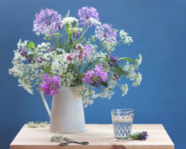 Mavi arka planda bir sürahi içinde yaz buketi.