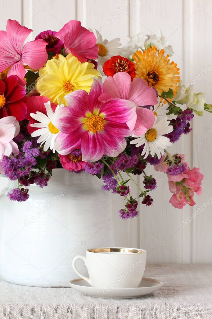 old dishes, a white cup and saucer on the table, and garden flowers. still life with a bouquet.