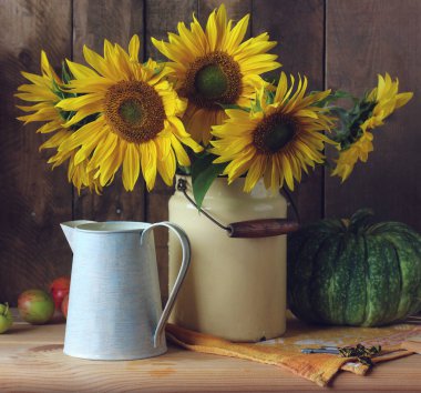 Masada bir buket ayçiçeği, balkabağı ve elma var. Kırsal bir yaz. Çiçekler ve meyvelerle dolu..