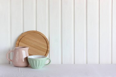 Mutfak lambası arka planı, boş bir masa, bulaşıklar ve kesim tahtası. Boşluğu kopyala.