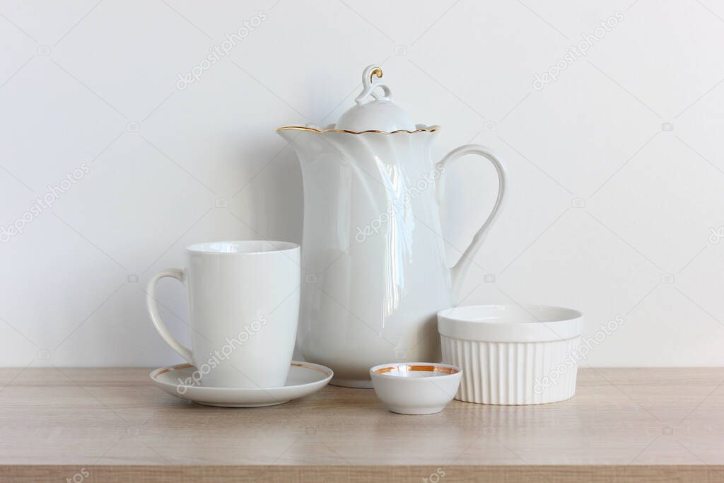 group of white dishes on the table. kitchen utensils on the shelf. coffee pot and mug.
