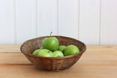 Tahta bir masada sepetteki yeşil elmalar. meyveler.