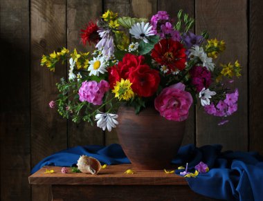 Kil bir sürahi içinde, arka planda bir buket bahçe çiçeği..