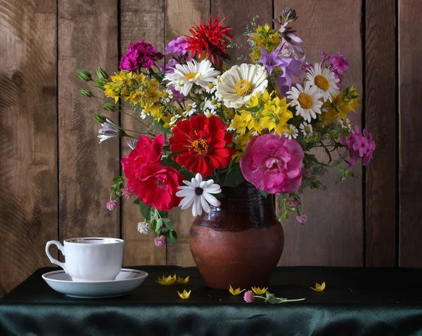 暗い背景のテーブルの上に花束とティーカップとソーサー 花瓶の中の花と共に生き — ストック写真
