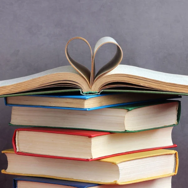 stack of thick hardcover books heart shaped pages education textbooks in color covers love to read