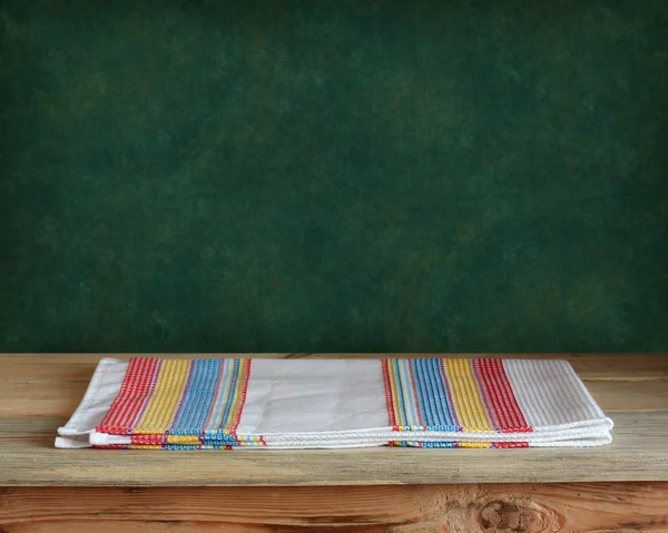 Table en bois avec une serviette contre un mur vert — Photo