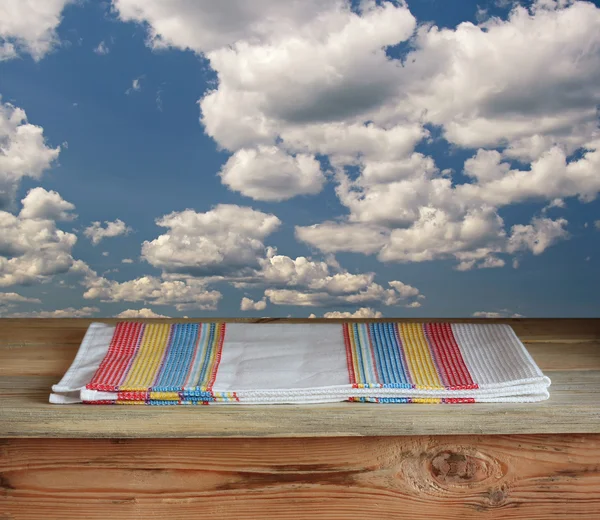 Mesa de madeira com uma toalha contra nuvens — Fotografia de Stock