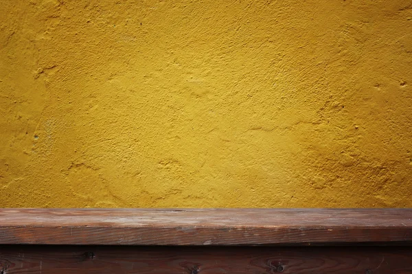 La mesa vacía contra la pared con el yeso que crece desnudo . — Foto de Stock