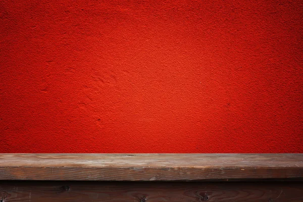 Empty wooden table against a red wall. — Stock Photo, Image