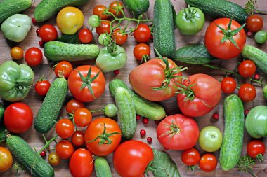Fresh cucumbers, cowberry, red and green tomatoes on a table.