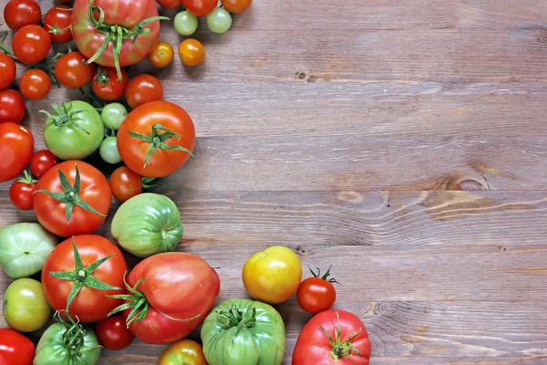 Los tomates frescos rojos y verdes sobre la mesa a la izquierda —  Fotos de Stock