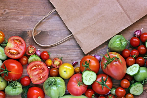 Свежие красные и зеленые помидоры, сегменты огурца и бумажной упаковки — стоковое фото