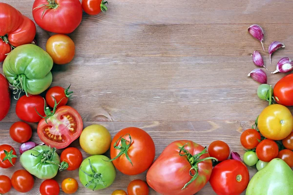 Φρέσκες ντομάτες κόκκινες και πράσινες και το σκόρδο σε ένα τραπέζι — Φωτογραφία Αρχείου