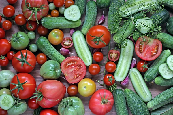 Pepinos frescos, alho, tomates vermelhos e verdes em uma mesa . — Fotografia de Stock