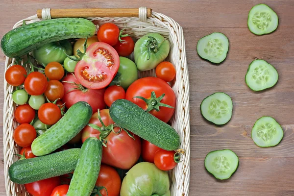 Pepinos frescos, tomates rojos y verdes en una canasta — Foto de Stock