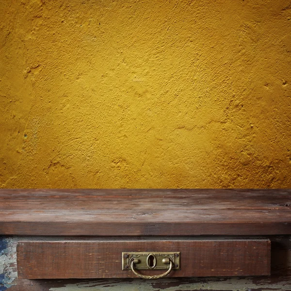 Empty wooden table against a yellow wall. — Stock Photo, Image