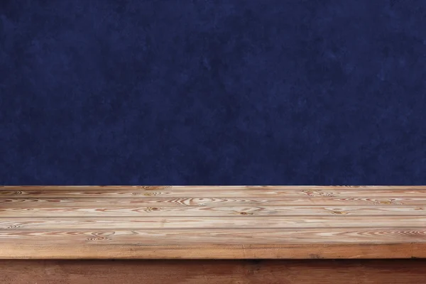 Prázdný dřevěný stůl u modré stěny. — Stock fotografie