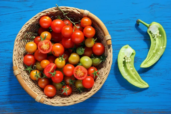 Tomates cherry rojos y amarillos en una canasta y pimienta verde —  Fotos de Stock