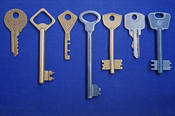 七把钥匙。蓝色背景上的钥匙. — 图库照片