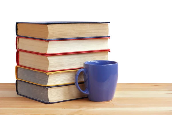Uma pilha de livros e uma taça na mesa, sobre um fundo branco . — Fotografia de Stock